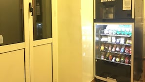A vending machine with a variety of beverages and snacks, located next to a door with a keypad lock. - Hotel Positano (Rome)