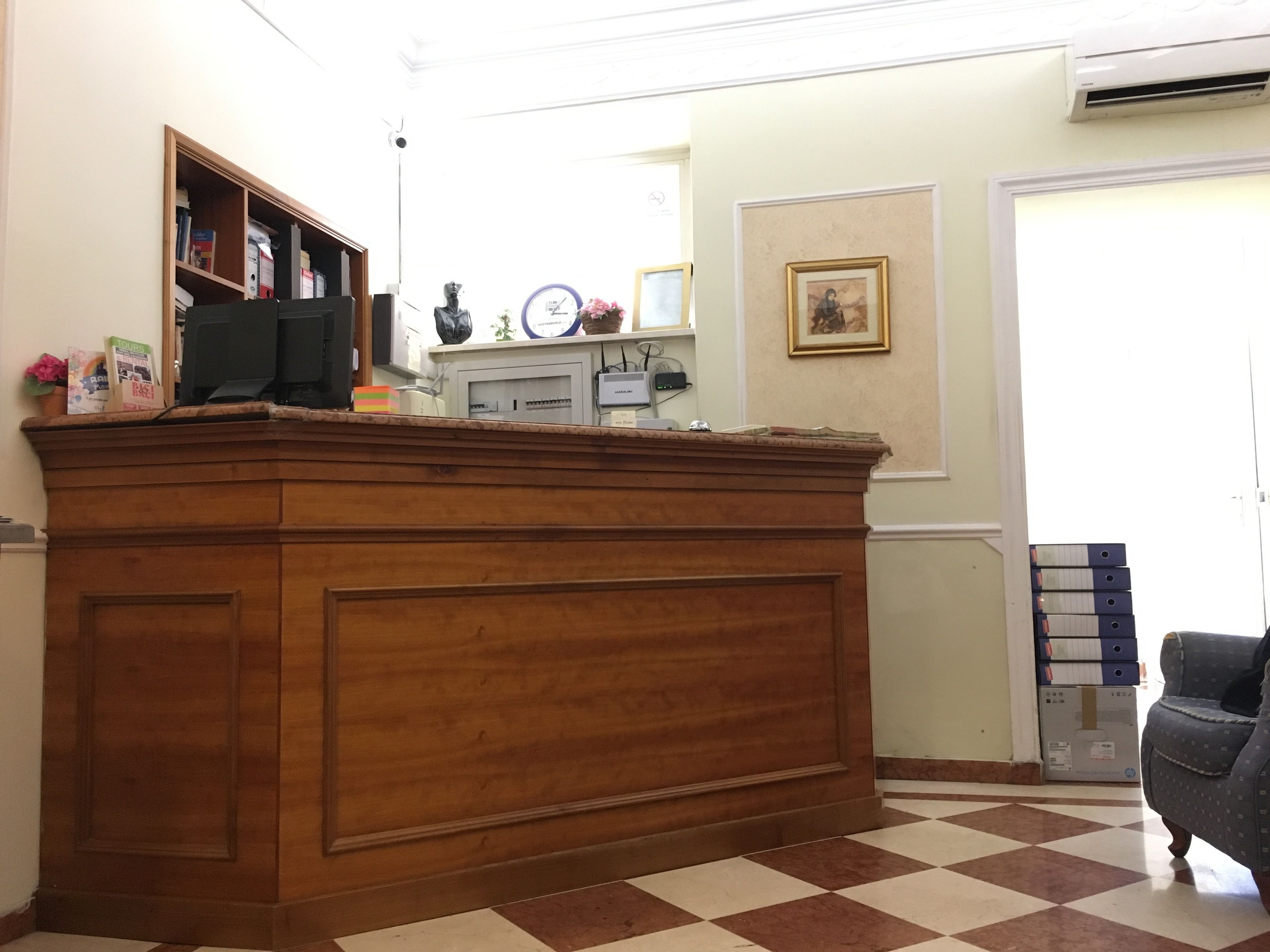 Una reception con pavimento a scacchi, una sveglia e un quadro incorniciato al muro.