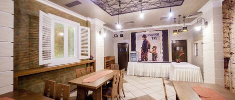 A restaurant with wooden tables and chairs, a tiled floor, and a ceiling with exposed beams.