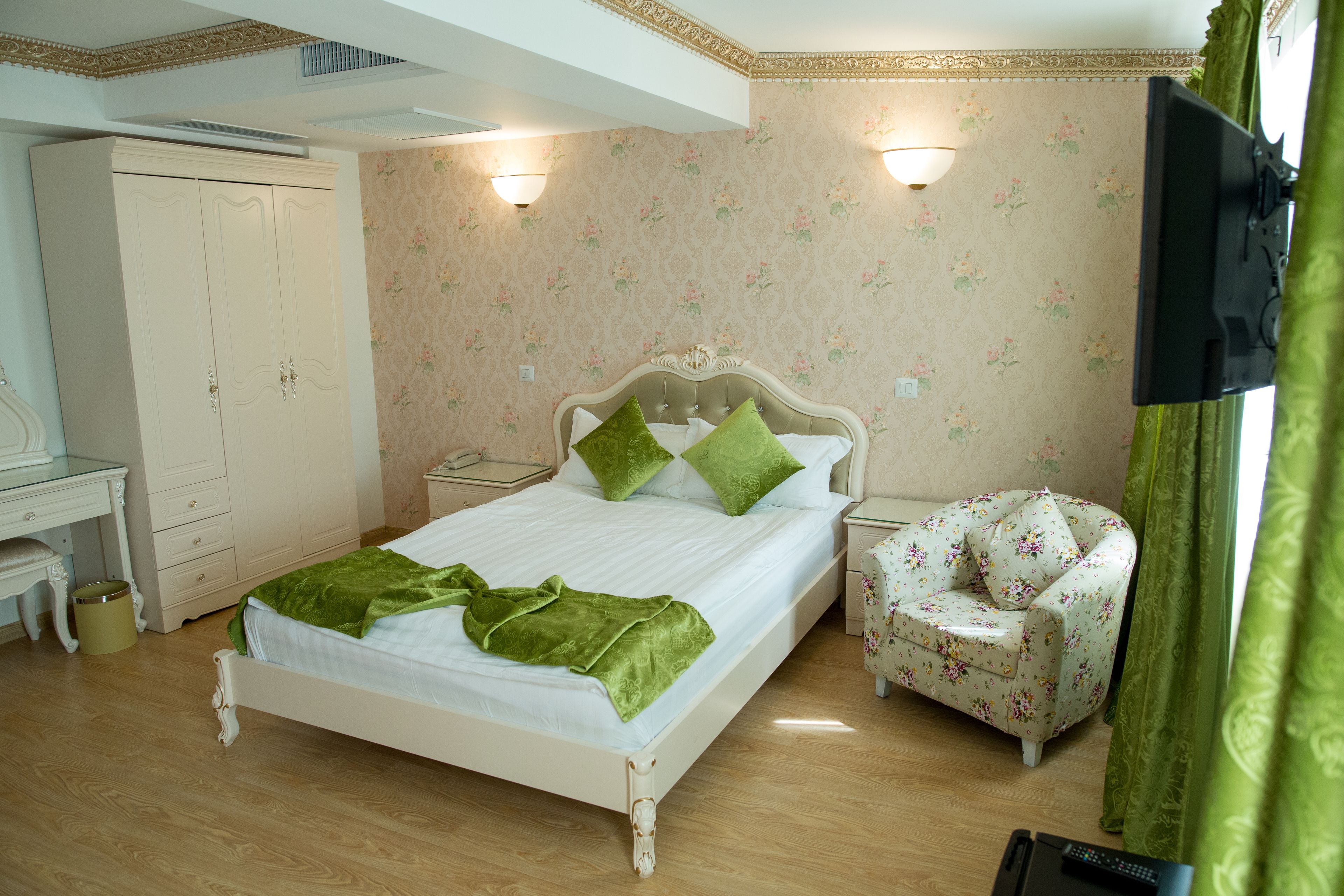 A bedroom with a bed, nightstands, a chair, a wardrobe, and a television.
