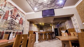 Un restaurante con techos altos, un mural de un edificio y una zona de bar.