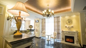 A luxurious living room with a marble floor, a fireplace, a chandelier, and elegant furniture. - Hotel Helin Central (Craiova)