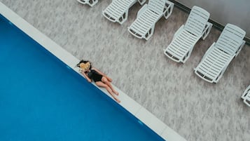 A swimming pool with white lounge chairs arranged along the edge.