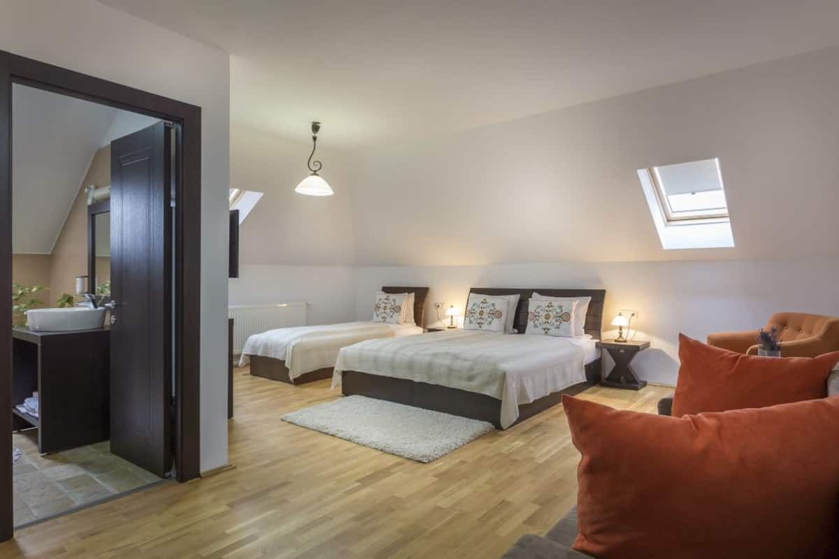 Une chambre avec deux lits, un coin salon avec un fauteuil, une petite table et une lucarne.