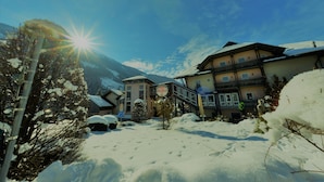 A snow-covered village with traditional buildings, a ski lift, and mountains in the background. - Flattacher Hof (Flattach)