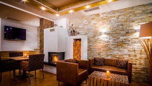 A modern living room with a stone wall, a fireplace, and a TV mounted on the wall. - Flattacher Hof (Flattach)