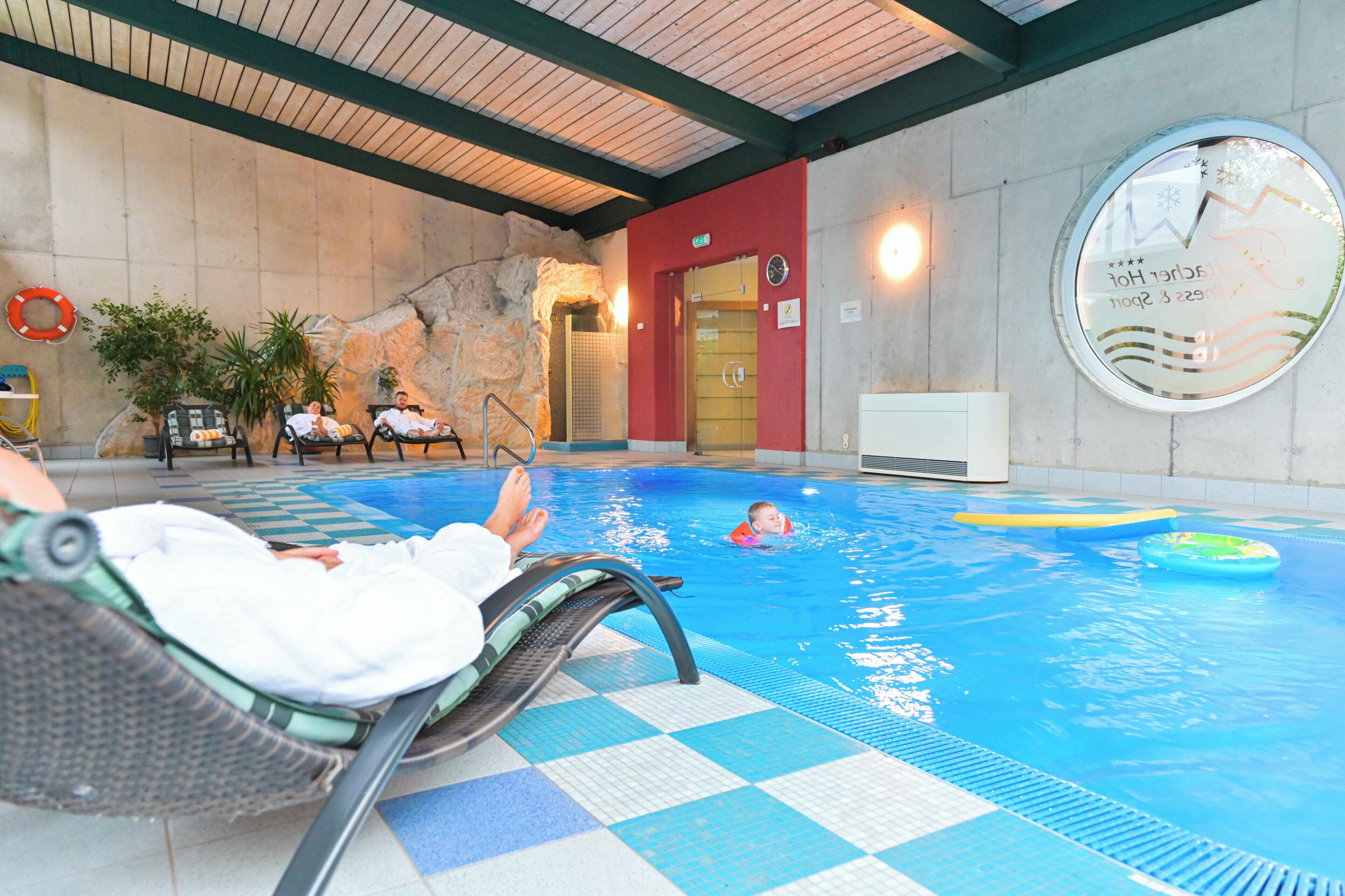 A pool area with lounge chairs, a lifebuoy, and a clock on the wall.