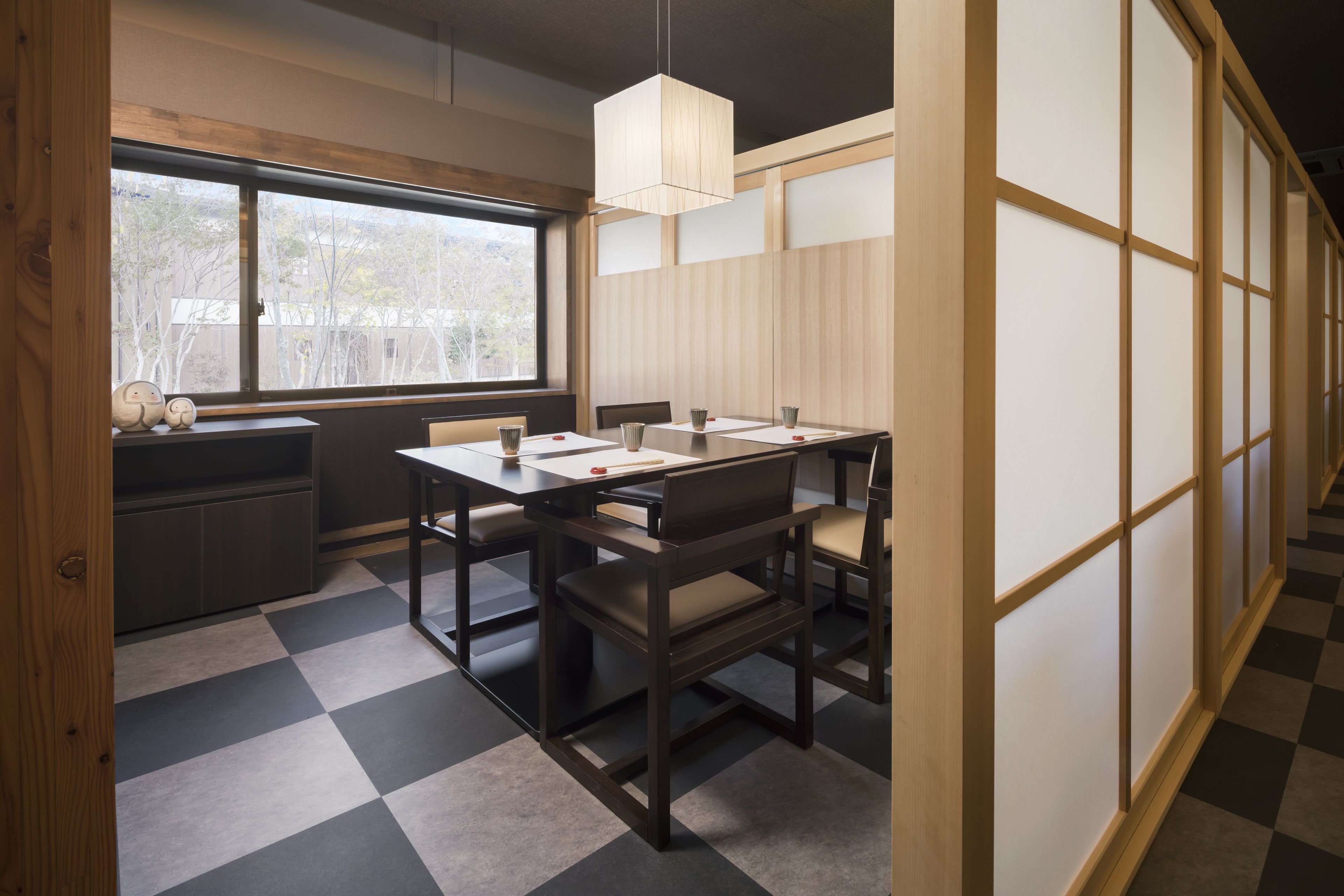 Una habitación tradicional japonesa con suelo de tatami, una mesa baja con cojines y puertas correderas shoji.