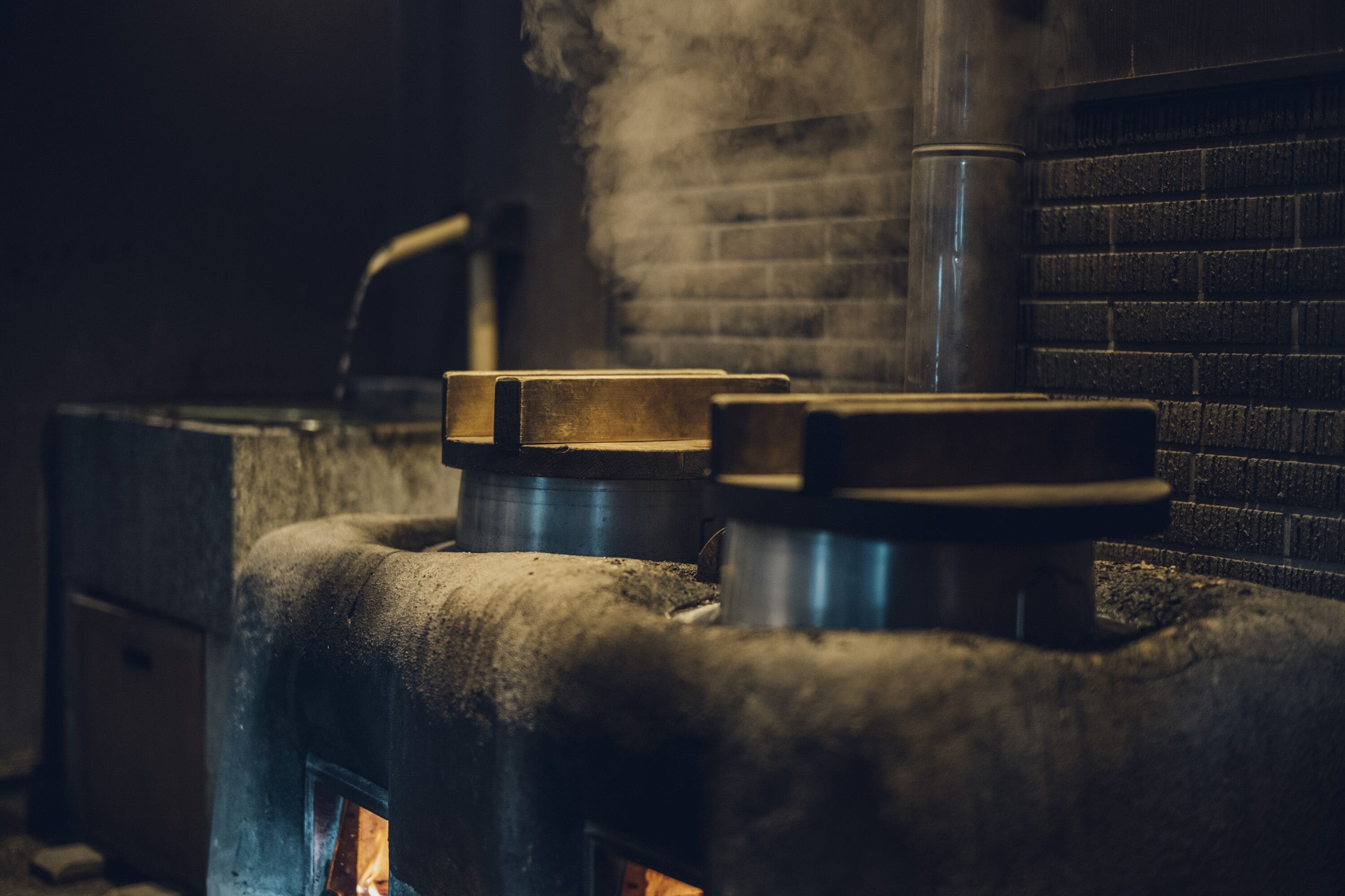 A wood-burning stove with a brick wall and a metal chimney.
