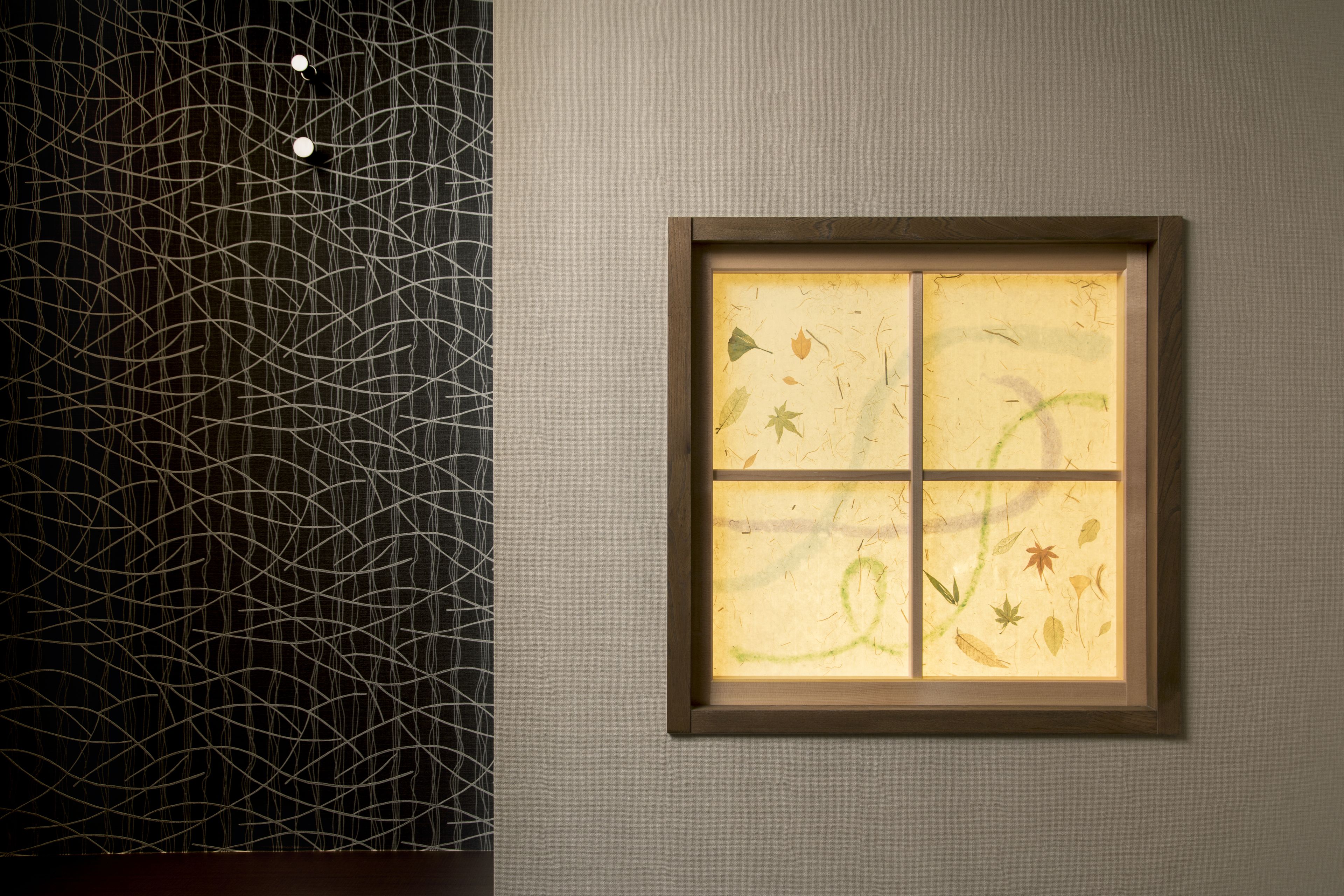 A framed artwork with abstract patterns and a window with a leaf design.