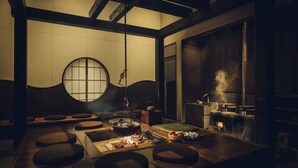 A traditional Japanese-style room with tatami mats, a low table with a fire, and a wood-burning stove. - Hoshino Resorts KAI Alps (Omachi)