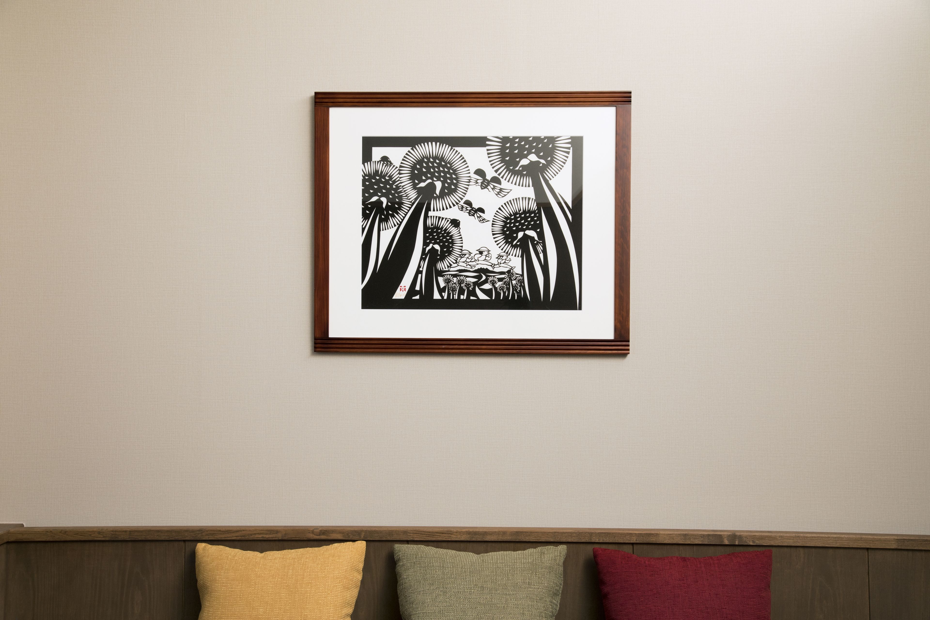 Una obra de arte en blanco y negro enmarcada en la pared sobre un banco de madera con cojines.