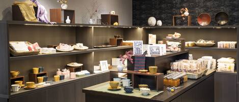 A modern retail space with shelves displaying various ceramic items, a central counter with packaged goods, and decorative elements like vases and bowls.