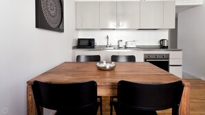 A modern kitchen with white cabinets, a wooden dining table, and black chairs. - Italianway   - Scarlatti (Milan)