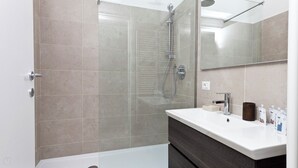 A modern bathroom with a glass-enclosed shower, a white sink, and a dark-toned vanity. - Italianway   - Scarlatti (Milan)