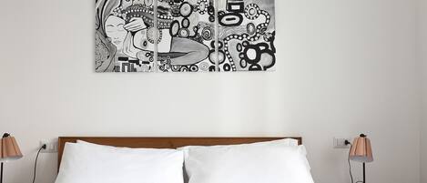 A bedroom with a wooden headboard, two bedside tables with lamps, and a large abstract artwork on the wall.