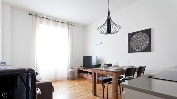A modern living room with a dining area, a flat-screen TV, and a dining table set for four. - Italianway   - Scarlatti (Milan)
