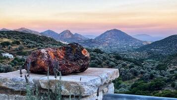 Una struttura in pietra con una grande roccia sulla sommità, affacciata su un paesaggio montuoso con una città sottostante.