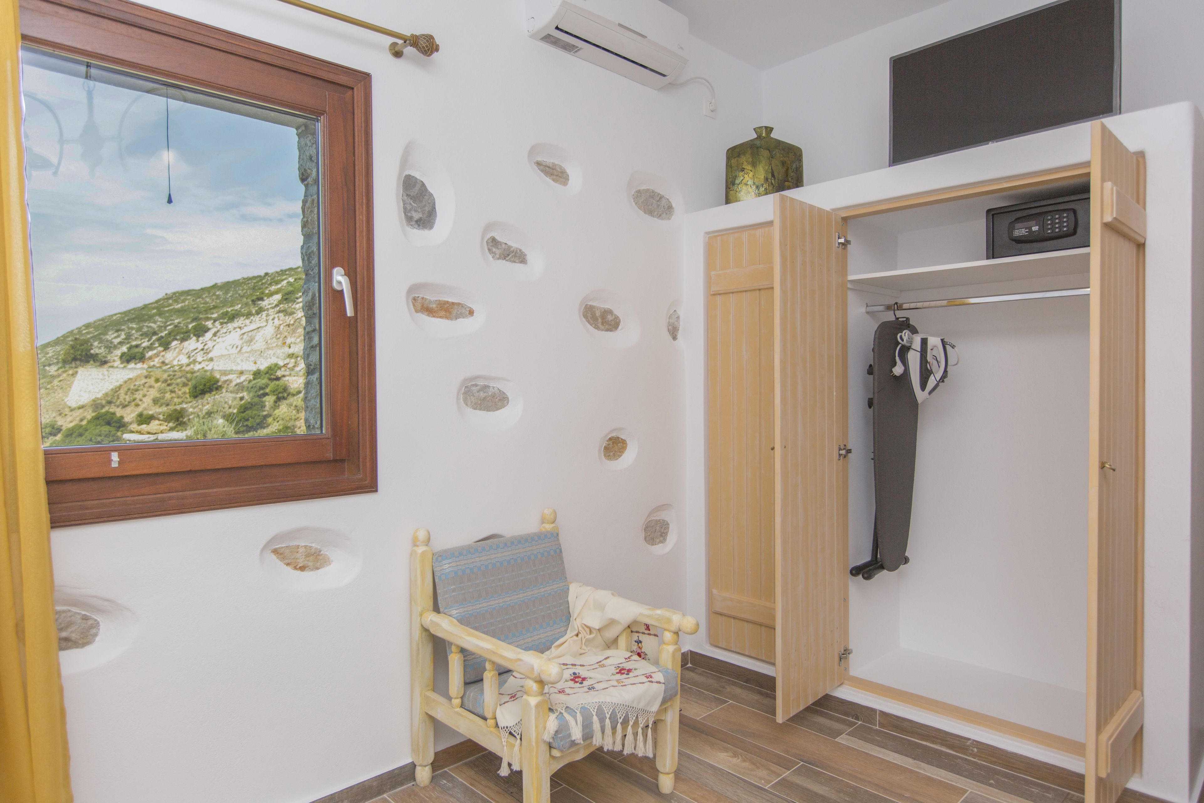 Une pièce avec une chaise en bois, une armoire et une fenêtre donnant sur un paysage.