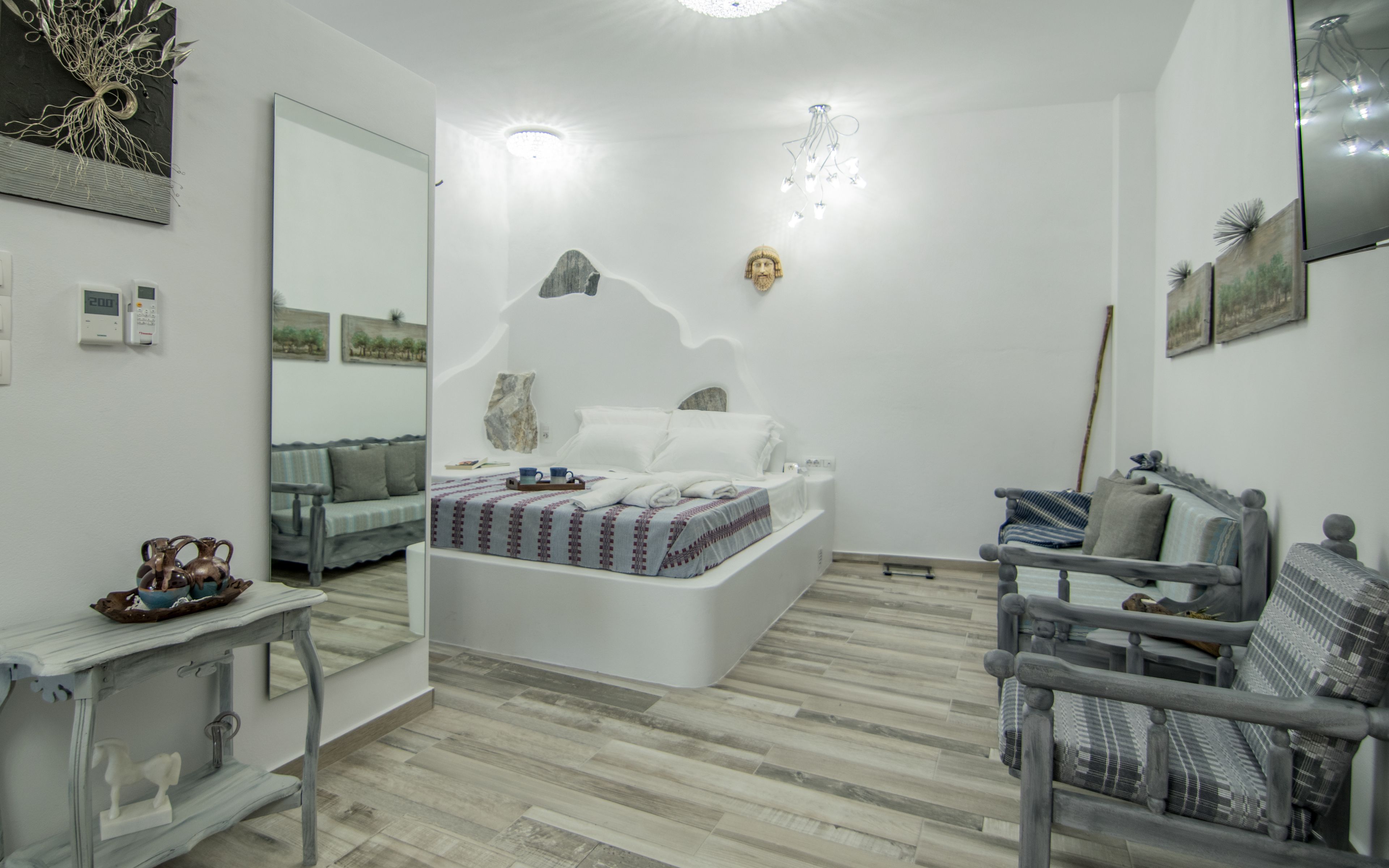 Une chambre à coucher comprenant un lit, un canapé, une chaise, une petite table et un miroir.