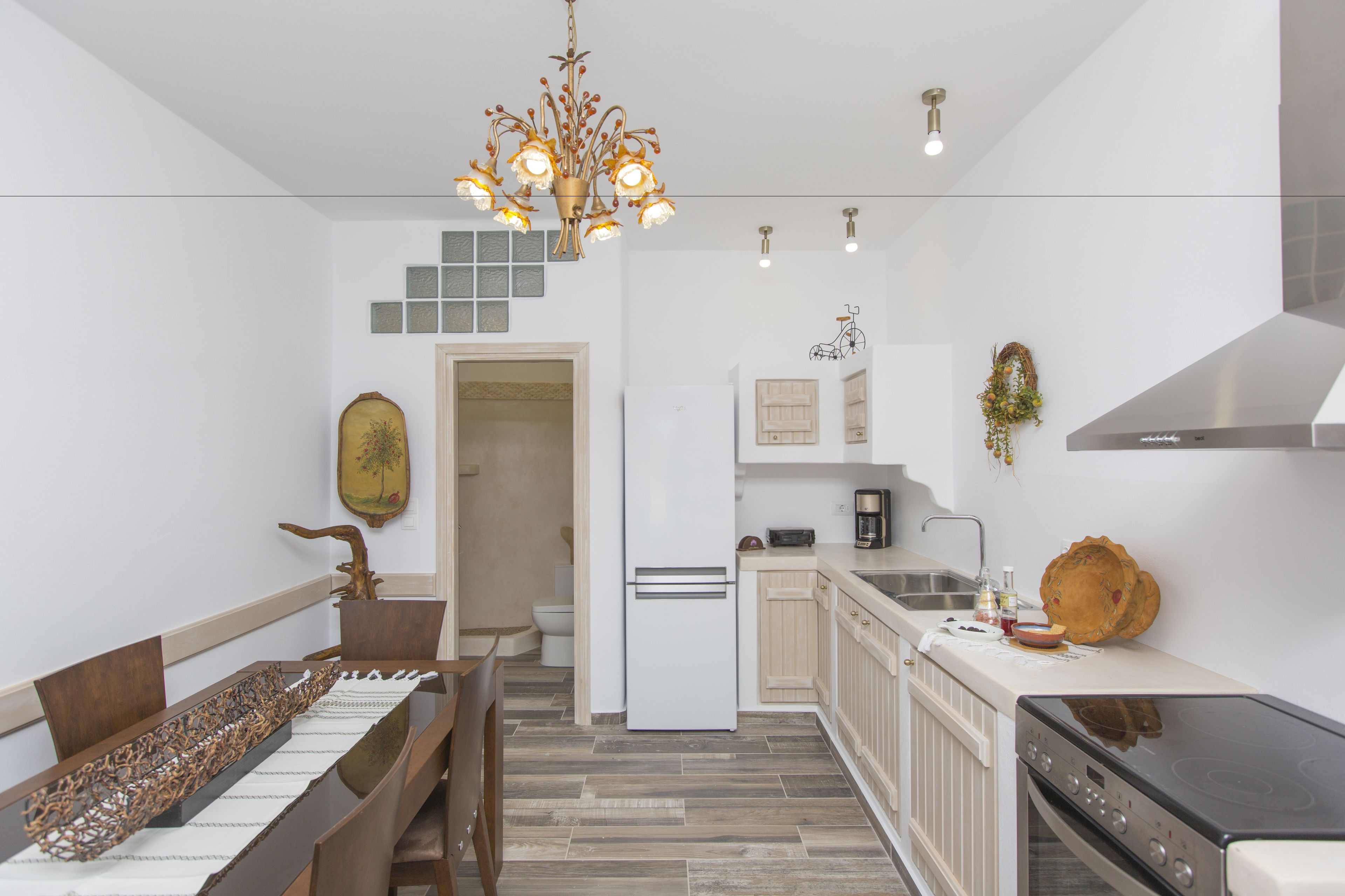 Una cocina moderna con una isla central, muebles blancos, un lavamanos de acero inoxidable y una estufa negra.