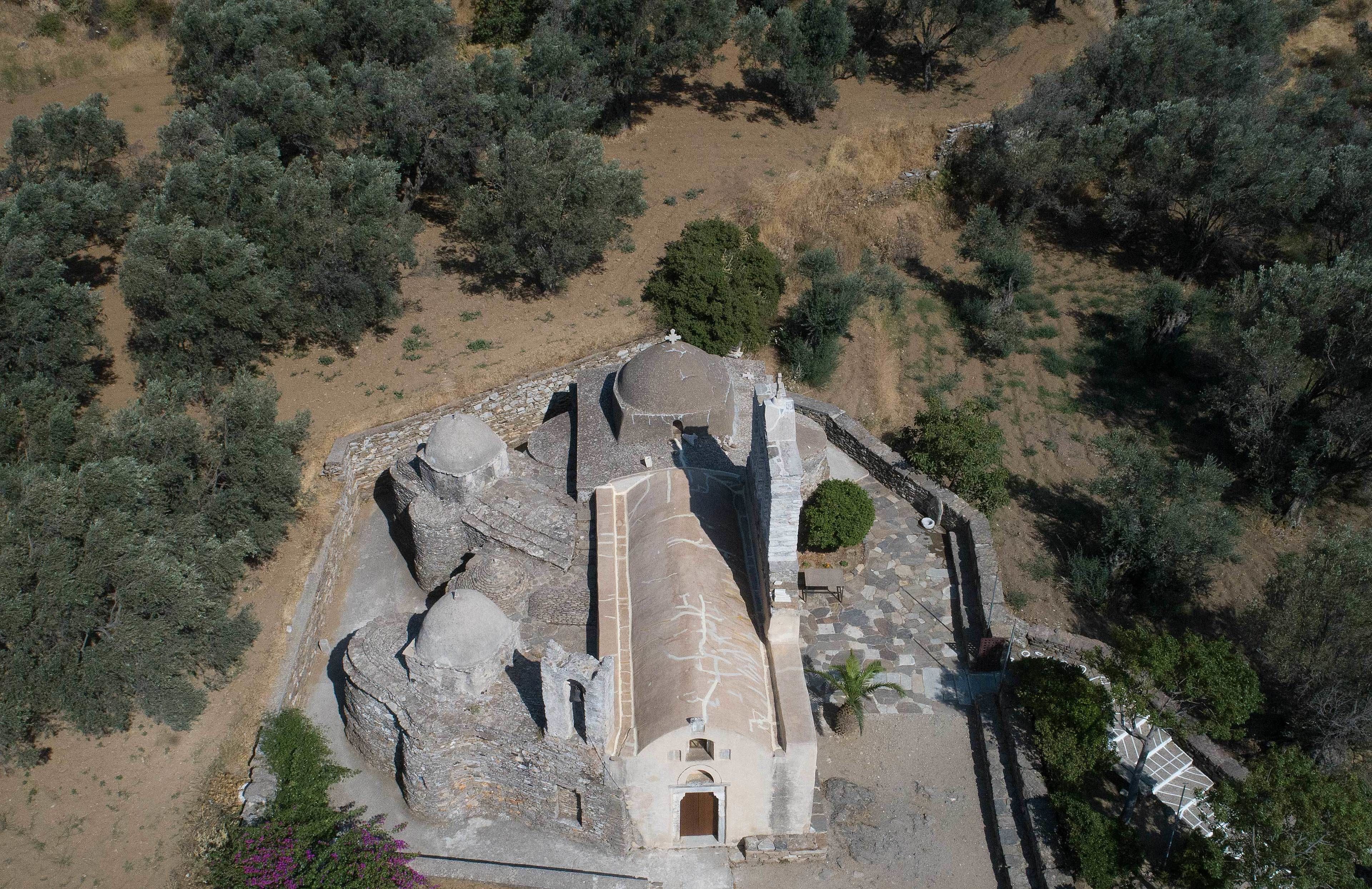 An aerial view of a historical building with a central dome, surrounded by rocky terrain and sparse vegetation.