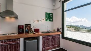 A kitchen with a view of mountains through a large window, a coffee maker, a toaster, and a sink.