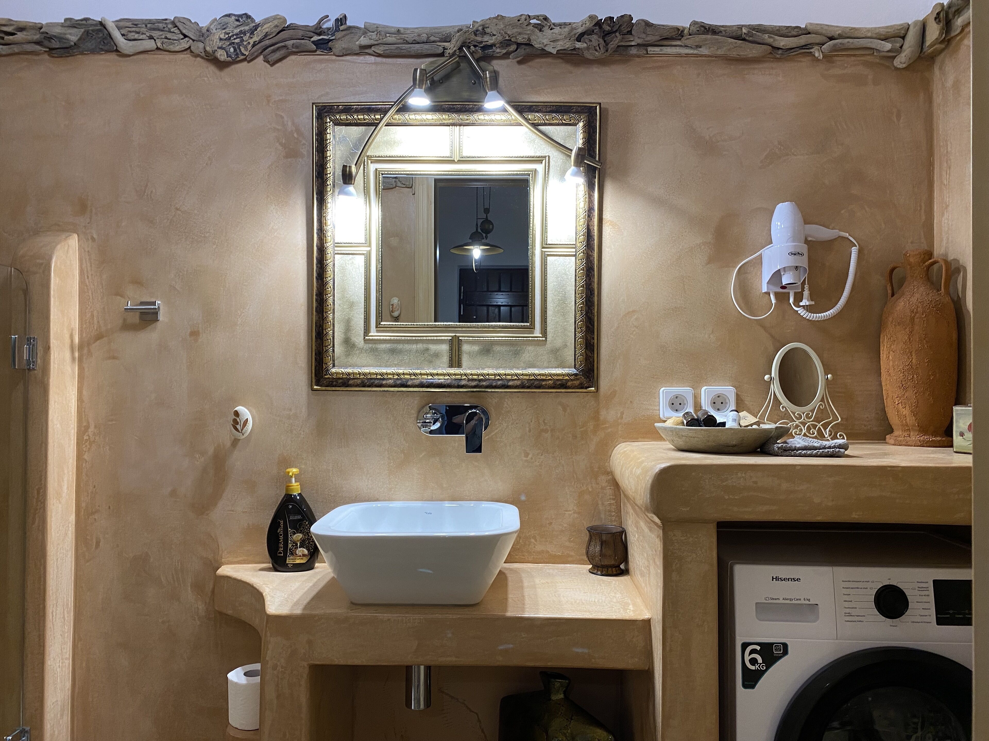 A bathroom with a sink, mirror, and a washing machine.