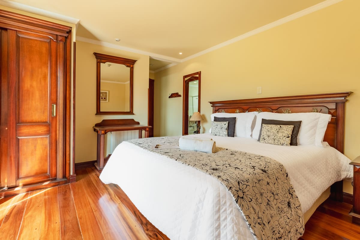 A bedroom with a large bed, wooden headboard, and a wooden wardrobe.