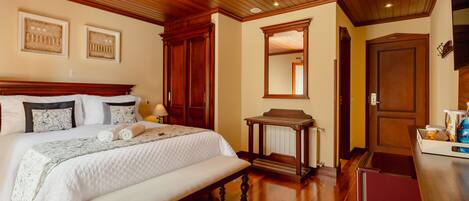 A bedroom with a large bed, wooden headboard, a bench, a nightstand, and a dresser.