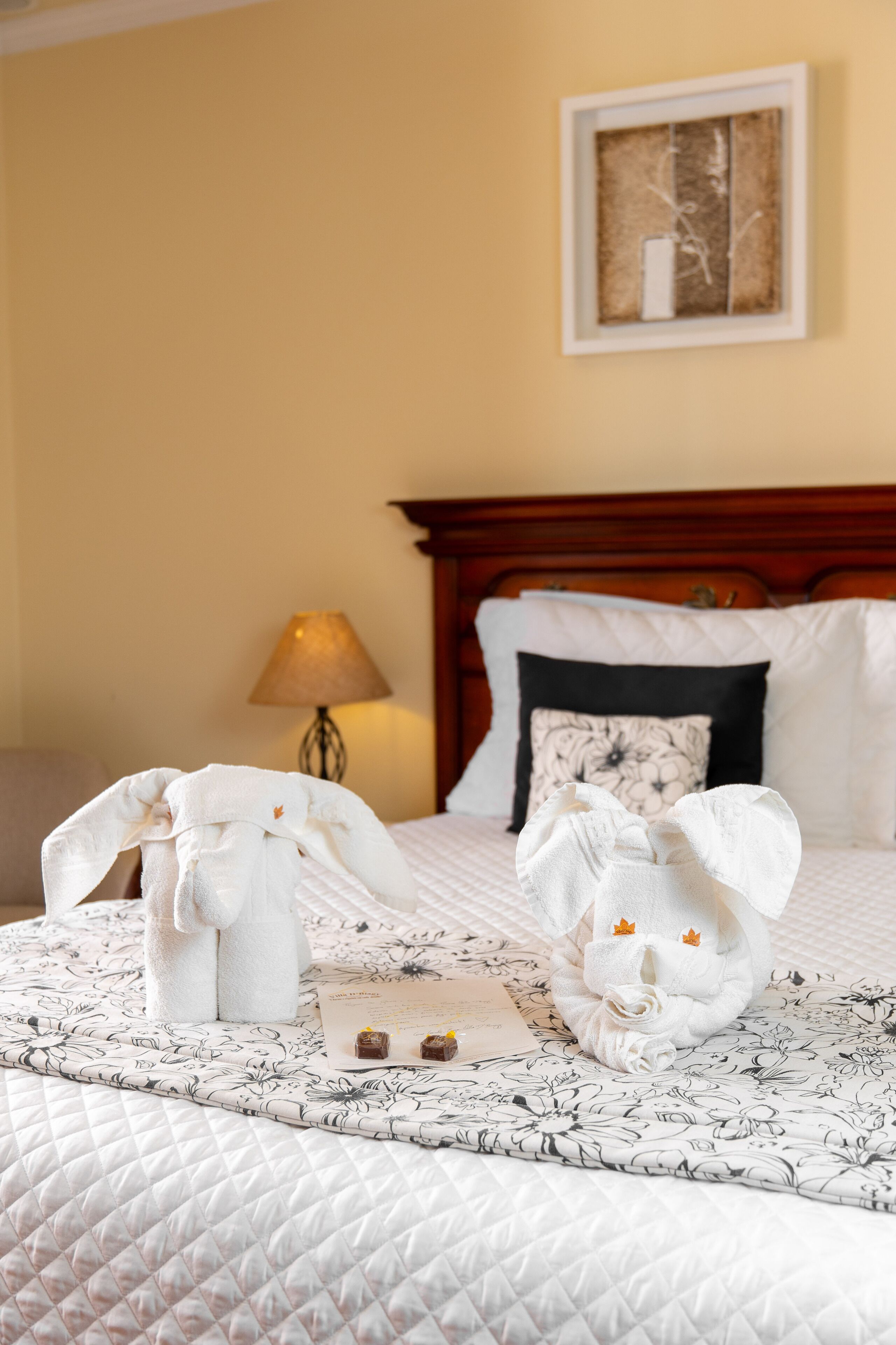 A hotel room with a bed, a nightstand, a lamp, and a framed picture on the wall.