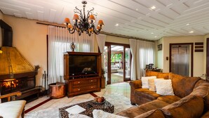 Una sala de estar con chimenea, televisor, sofá y candelabro.