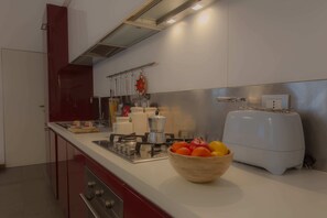 Uma cozinha moderna com eletrodomésticos de aço inoxidável, uma tigela de frutas de madeira no balcão e uma torradeira.