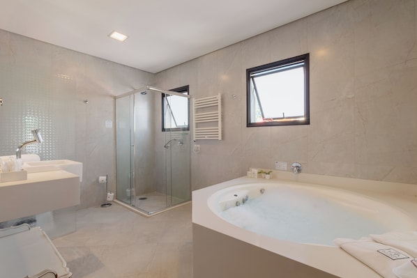 A modern bathroom with a freestanding bathtub, a glass shower enclosure, and a large window providing natural light. - Pousada D'Biagy Premium (Campos do Jordão)
