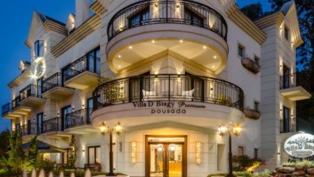 Un hôtel à plusieurs étages, doté d’un toit triangulaire distinctif, de nombreux balcons et d’une entrée bien éclairée.