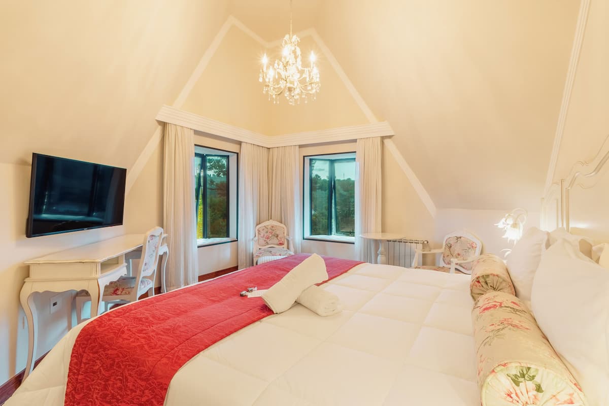 Een slaapkamer met een groot bed, een televisie, een bureau en twee stoelen.