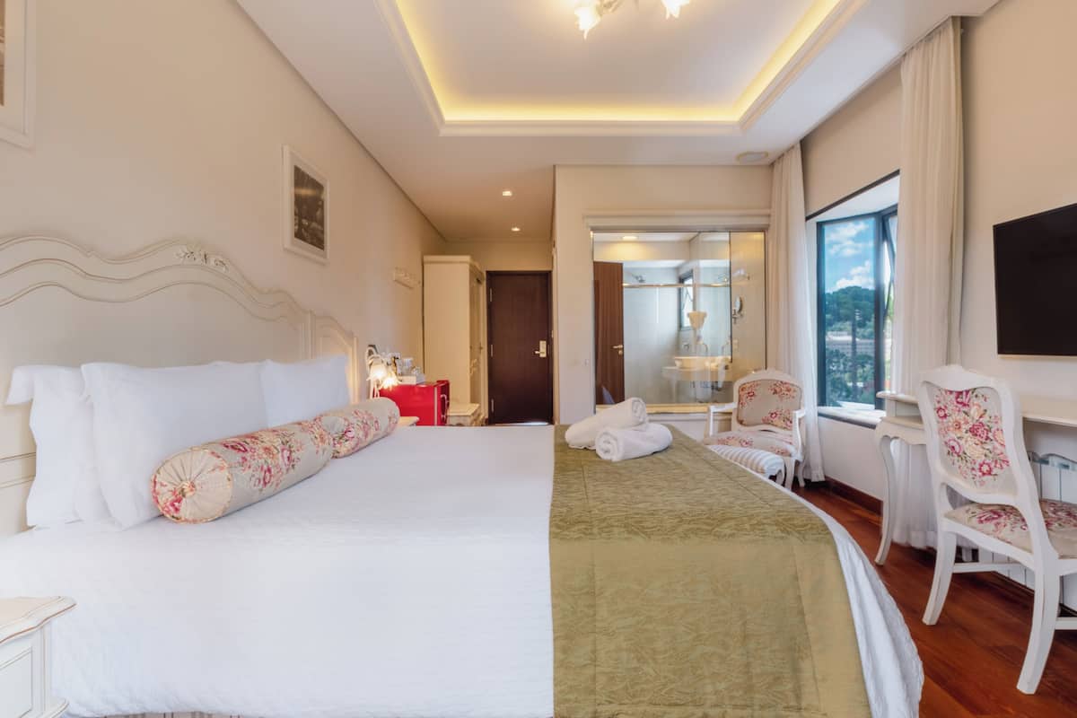 Een hotelkamer met een groot bed, een bureau, een stoel en uitzicht op de omgeving.