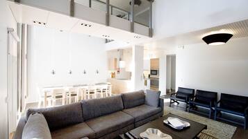 Un salon moderne avec un canapé gris, une table basse et, au fond, un coin repas.