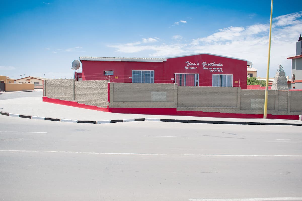 Um edifício vermelho com uma placa que diz "Tina's Guesthouse" e informações de contato.