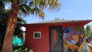 A small red building with a colorful mural on the side, a door, and a window.