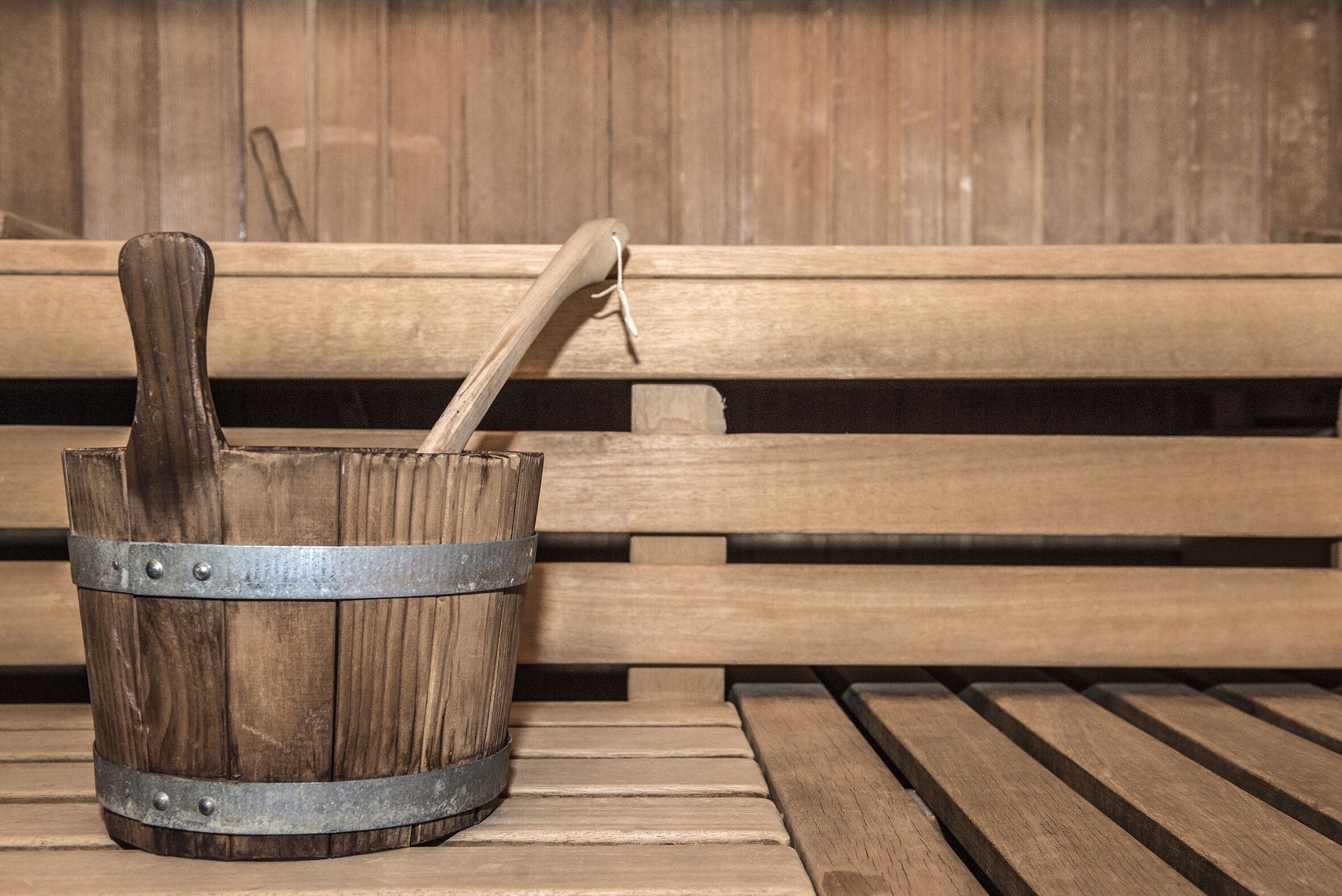 A wooden bench with a metal bucket placed on it.