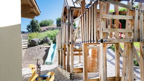 Una estructura de juego de madera con un tobogán y elementos para escalar.