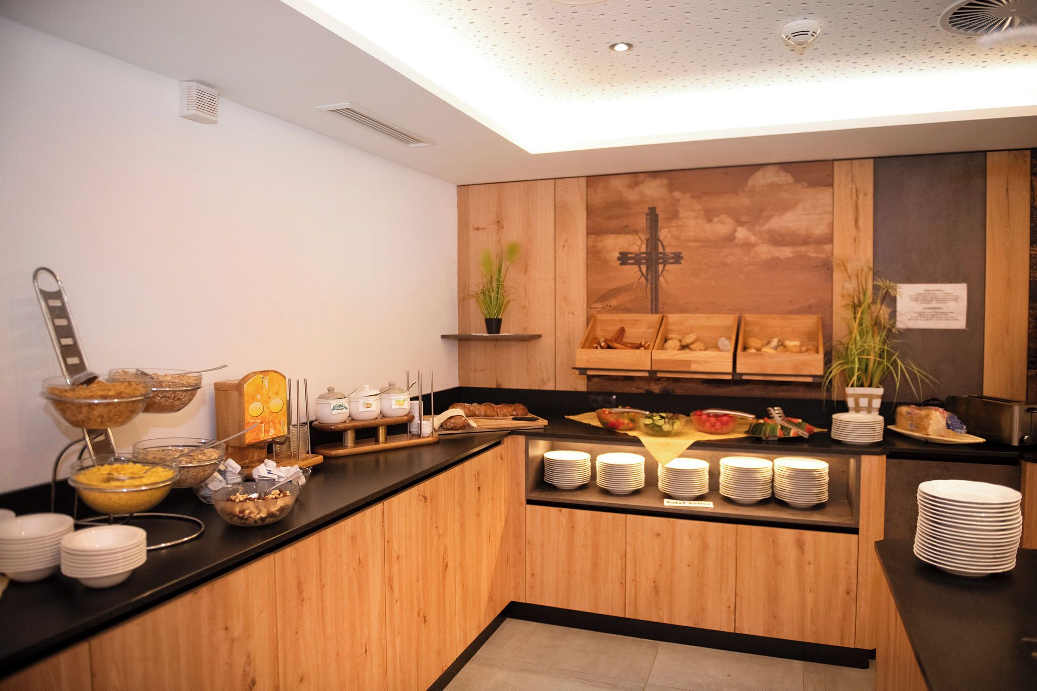 A breakfast buffet area with various food items, a coffee station, and a wooden counter.