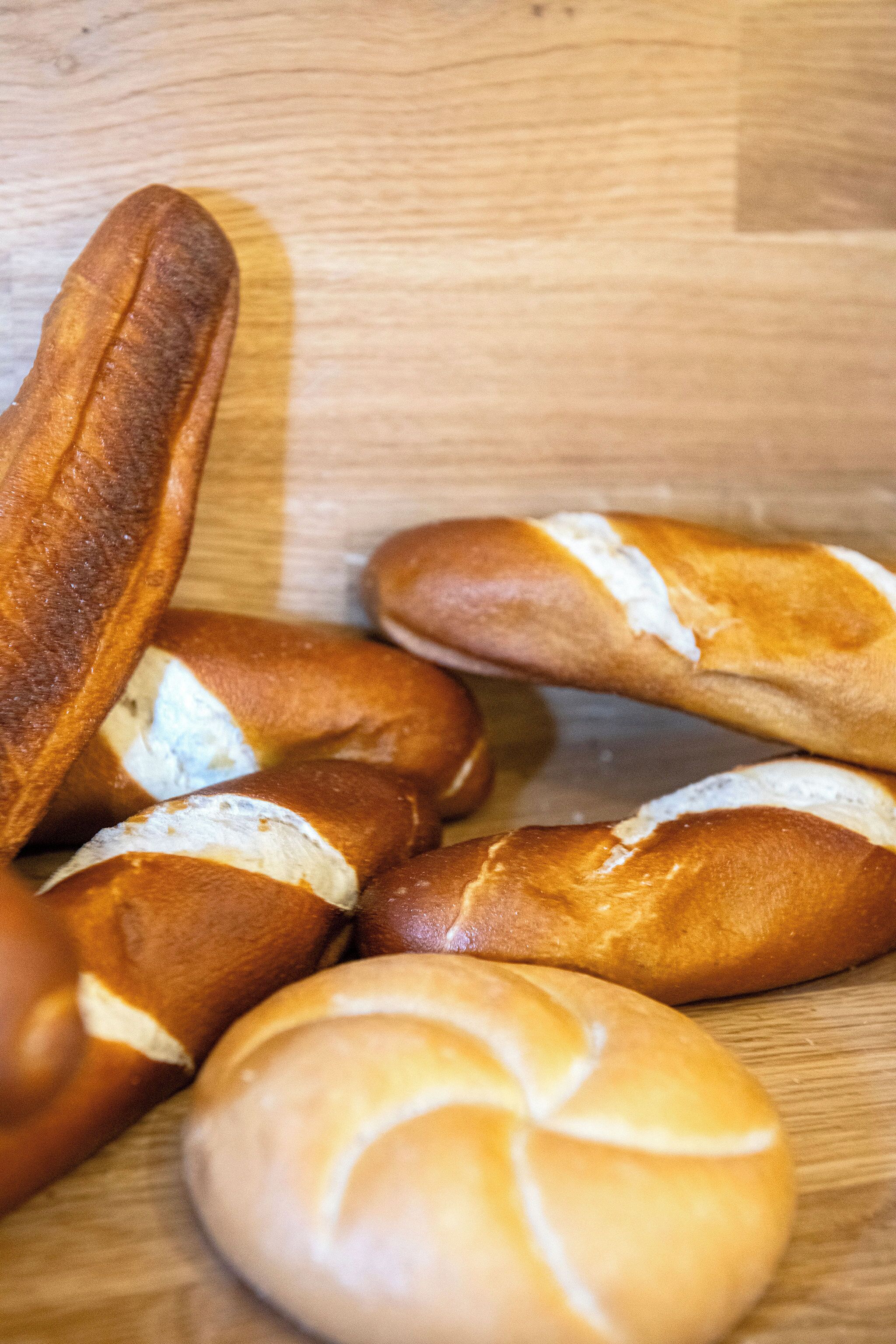 A wooden surface with several loaves of bread, some with visible white fillings.