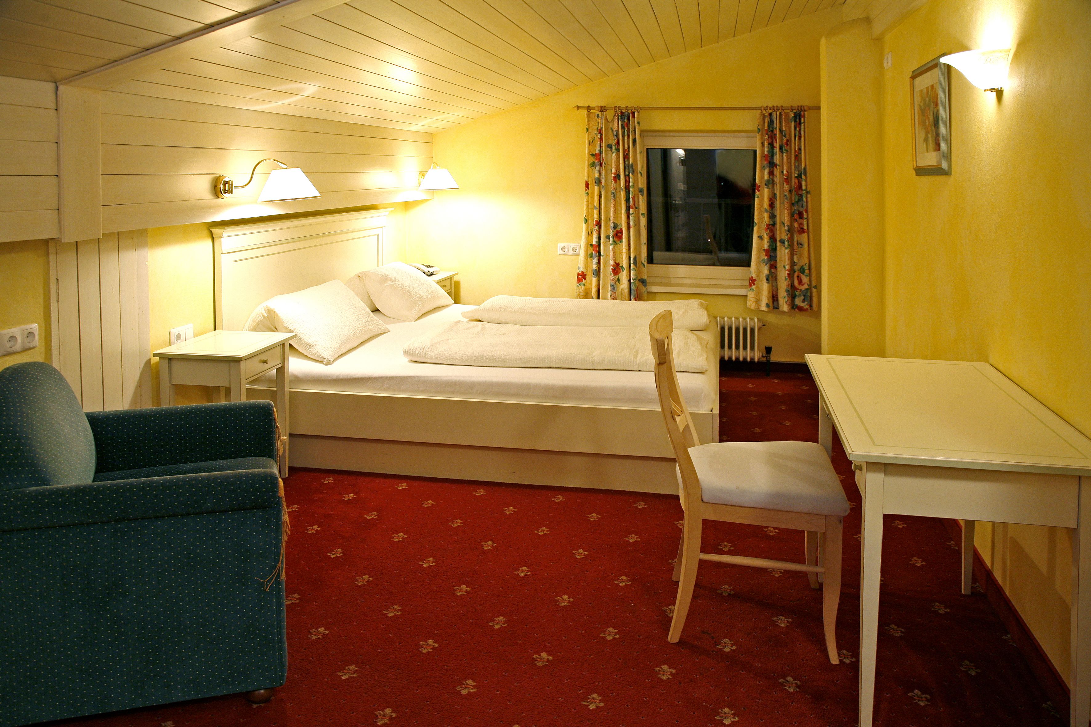 Una habitación de hotel con una cama, una silla, una mesa y un escritorio.