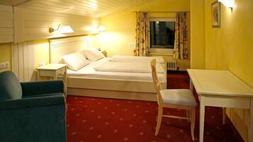 Una habitación de hotel con una cama, una silla, una mesa y un escritorio.