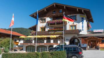 A hotel with a balcony, flags, and a sign for a restaurant.