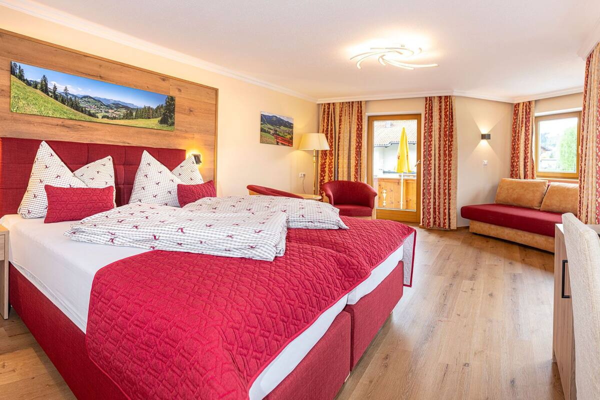 Une chambre d’hôtel avec un grand lit, un canapé, un bureau avec une bouilloire et une télévision.