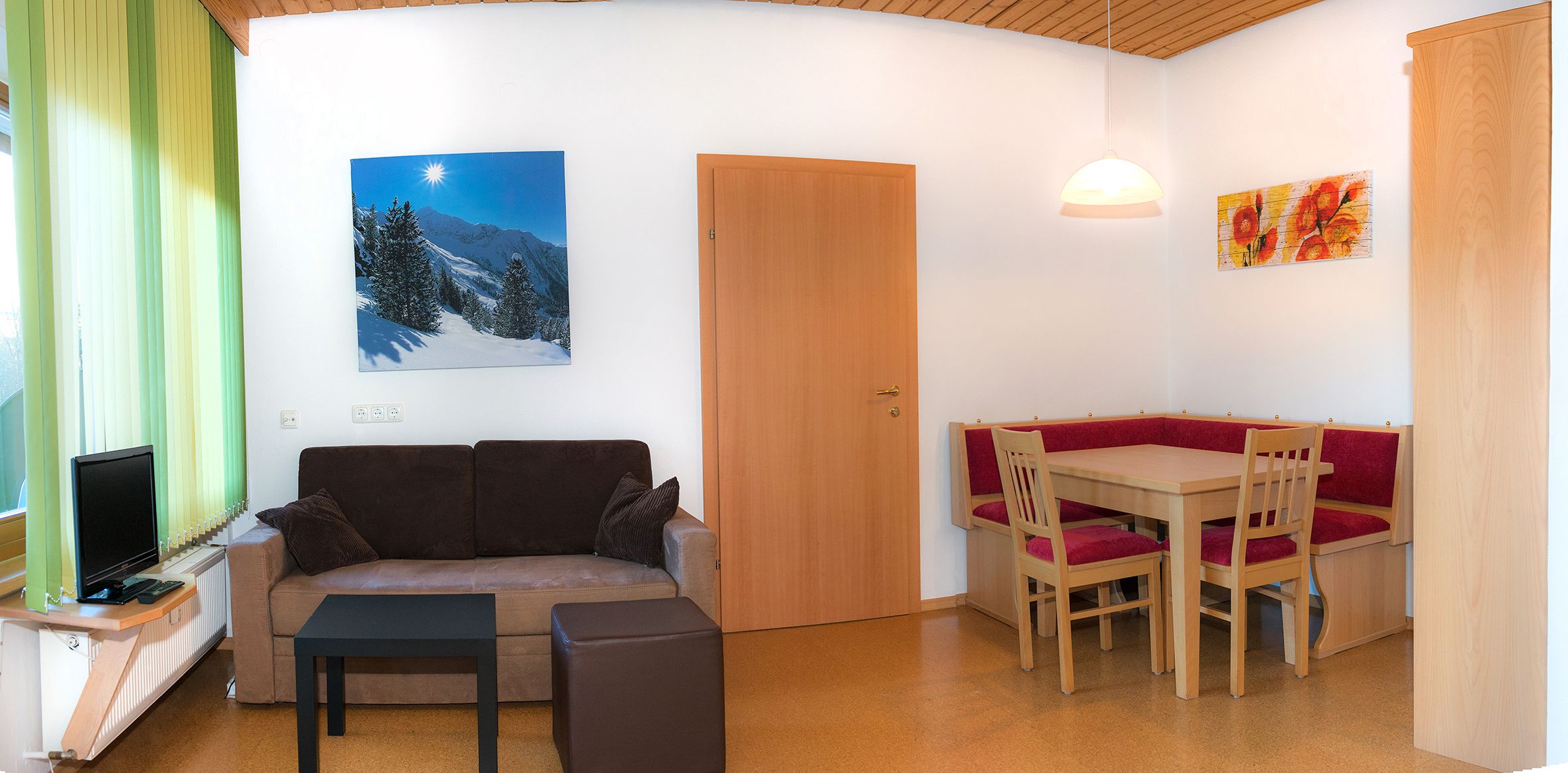 Una sala de estar acogedora con un sofá, una mesita, un televisor y un comedor con una mesa de madera y sillas.
