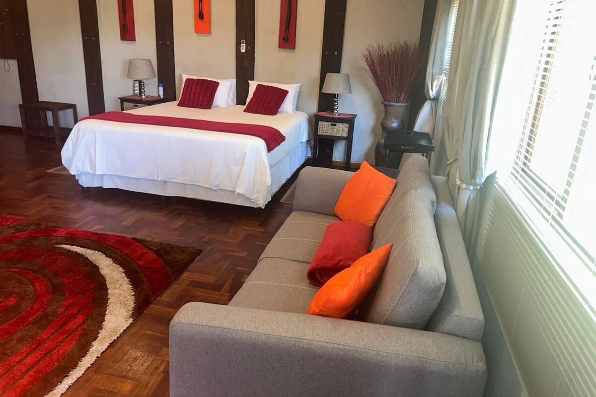 A hotel room with a bed, a sofa, and a large window.